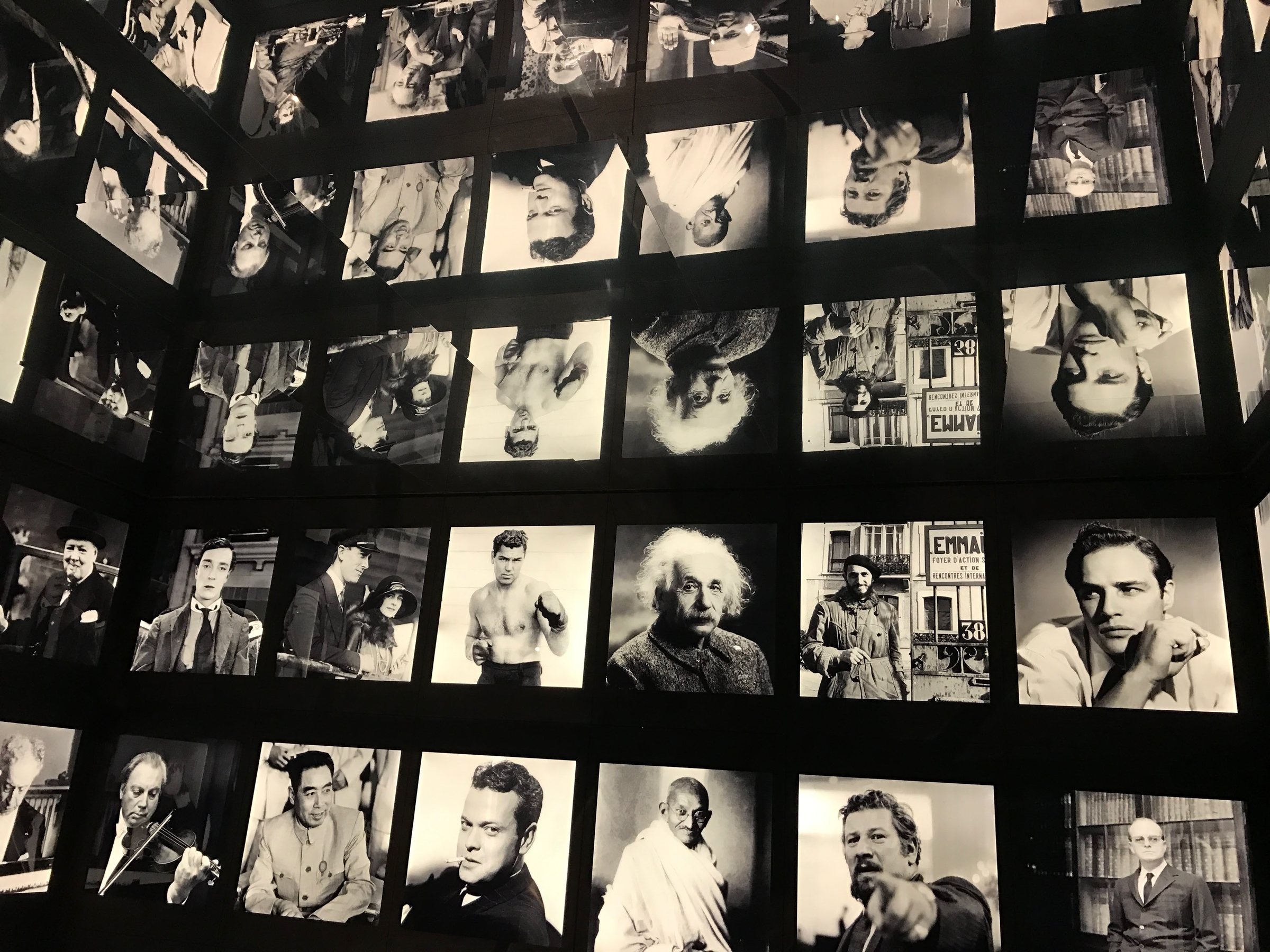 Un mur de portraits en noir et blanc de personnalités célèbres.