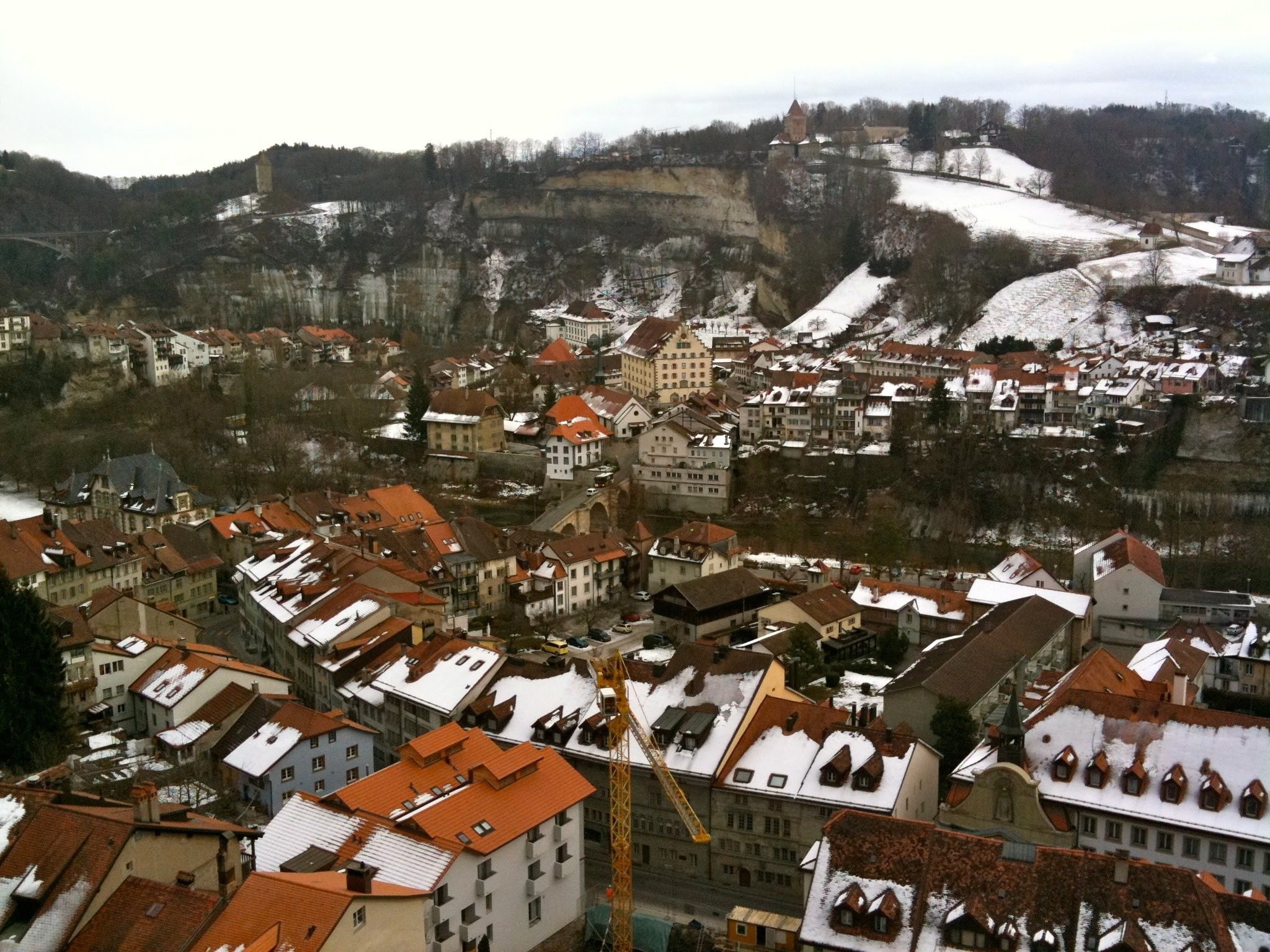 Fribourg enneigée vue d'en haut, ses toits rouges et blancs.